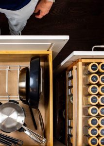 Neatly organized kitchen drawers with professional organizer standing near by