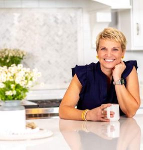 Susan Stewart, professional organizer, sitting in a kitchen with a cup of coffee
